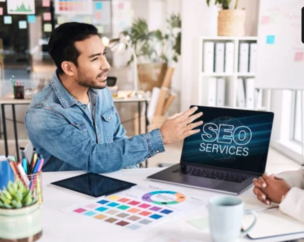 Professional workspace setup illustrates systematic approach to AI-powered SEO implementation Business professional seated at office desk presenting SEO services on laptop screen, representing the systematic methodology of implementing AI-driven search optimization strategies.
