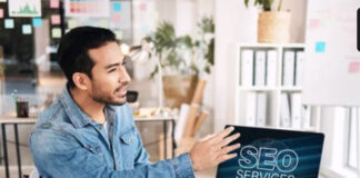 Your Step-by-Step Guide to AI SEO Business professional seated at office desk presenting SEO services on laptop screen, representing the systematic methodology of implementing AI-driven search optimization strategies.