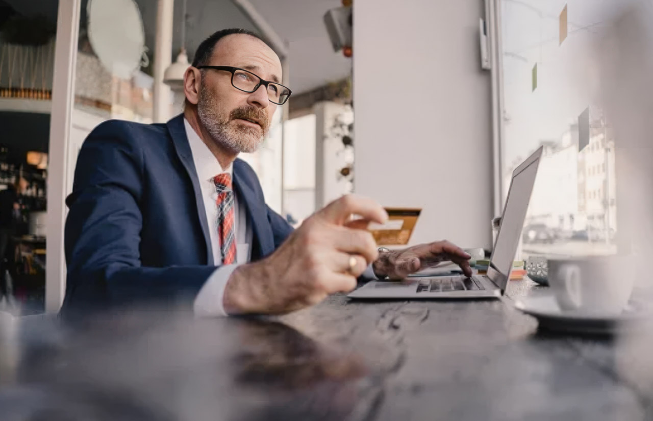 Professional man in blue suit and glasses working on laptop at wooden desk in bright modern office, representing independent technical SEO implementation.