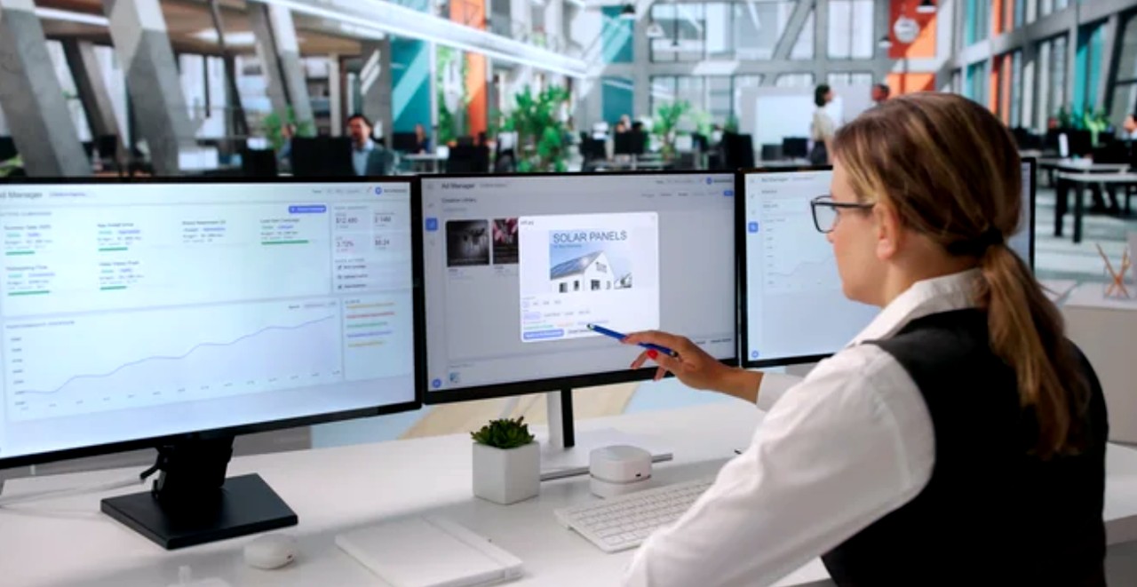 Professional working at a triple-monitor workstation in a bright modern office, representing contemporary approaches to future-proofing website development and digital workflows.
