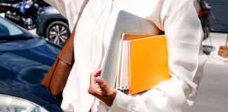 Professional in white blazer carries laptop and colorful notebooks on city street, representing the preparedness needed for adapting to Google SGE search changes.