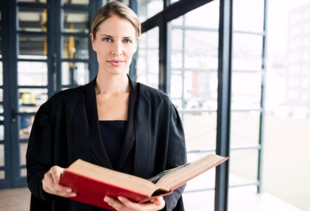 Professional woman with book in contemporary workspace symbolizes rise of women-focused business platforms in Africa Woman in formal black attire holds an open red book in a light-filled modern office, representing the growth of women-focused business directory platforms across Africa.
