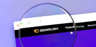 Magnifying glass held up to computer screen displaying SEMRUSH analytics website, representing the detailed attention required for website error monitoring and maintenance.