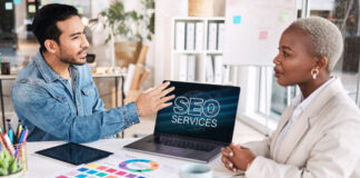The Synergistic Relationship: How Directories Strengthen Your Google Ranking Two business professionals meet at a desk with a laptop displaying SEO services, discussing strategies for strengthening directory listings and search engine rankings.