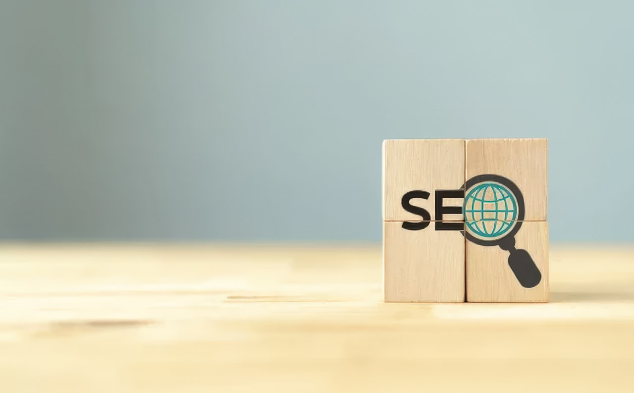 Four wooden blocks printed with SEO text and magnifying glass icons arranged on a wood surface, representing search engine optimization and website crawlability concepts.