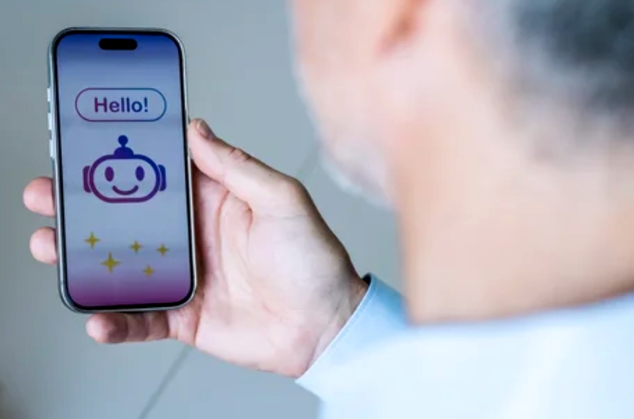 Person holds smartphone showing chatbot interface with robot icon and greeting text, illustrating conversational AI technology used in voice branding and smart device marketing.