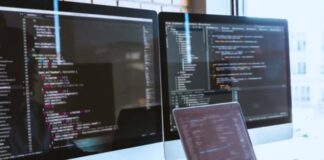 How to Future-Proof Your Website A software developer's workspace with laptop and dual monitors displaying code editors on a white desk, representing the technical environment for building adaptable websites.