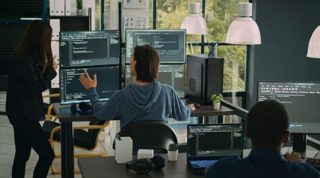 Development team workspace exemplifies collaborative approach to identifying and fixing website problems Software developers working at multiple monitors displaying code in a modern office workspace, illustrating the collaborative technical process of diagnosing and resolving website issues.