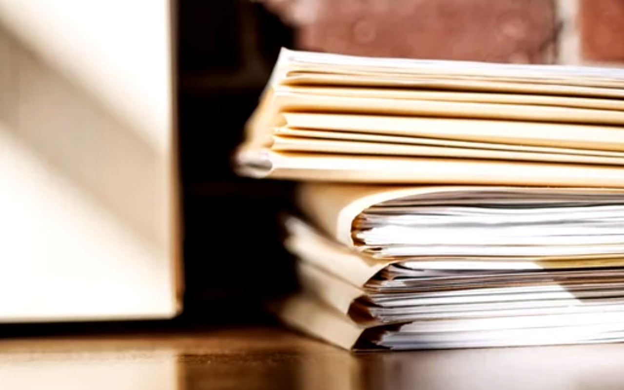 Stack of magazines and notebooks beside a laptop on an office desk, representing documentation and resources used in national business directory verification.
