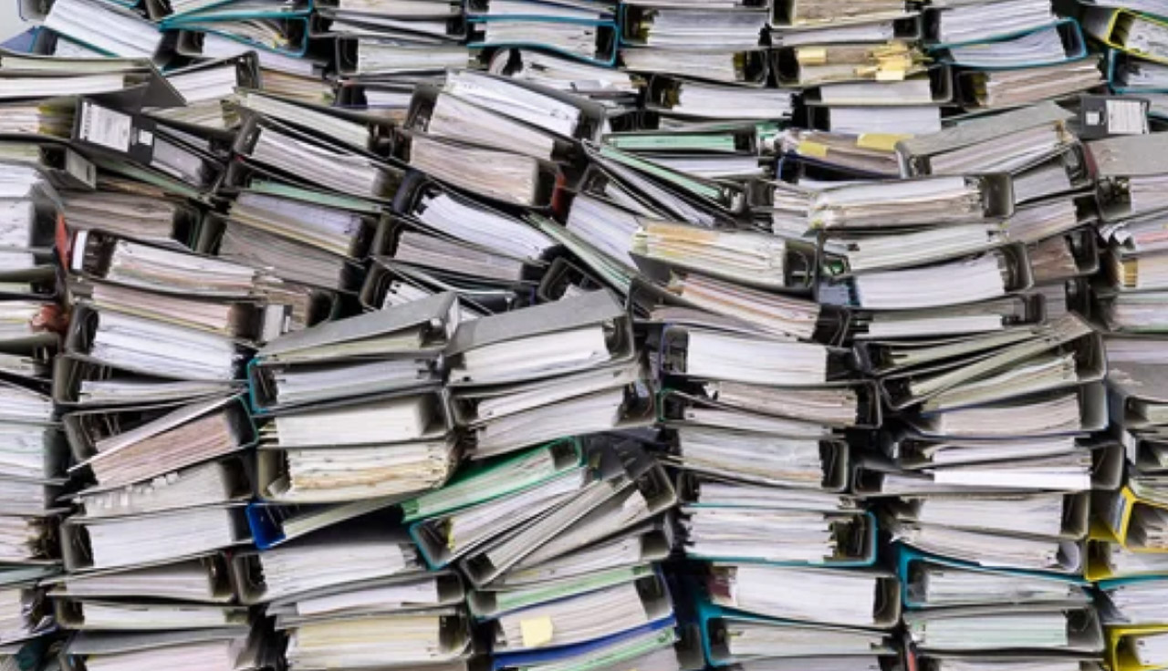 Multiple ring binders stacked densely together showing colorful spine edges and filed papers, representing the documentation involved in business directory registration processes.