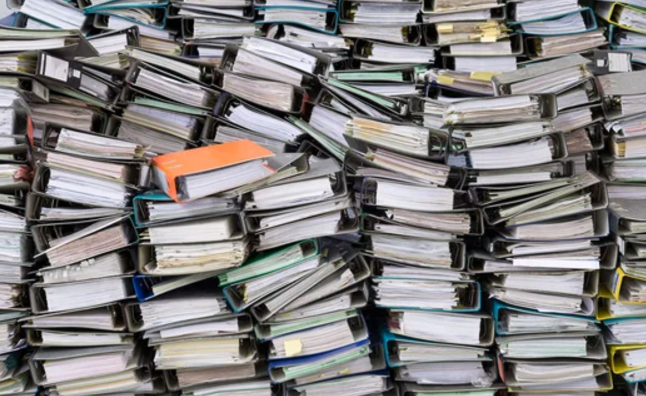 Stacked office ring binders in black, turquoise, and orange colors filled with papers, representing the organizational framework behind curated directory systems.