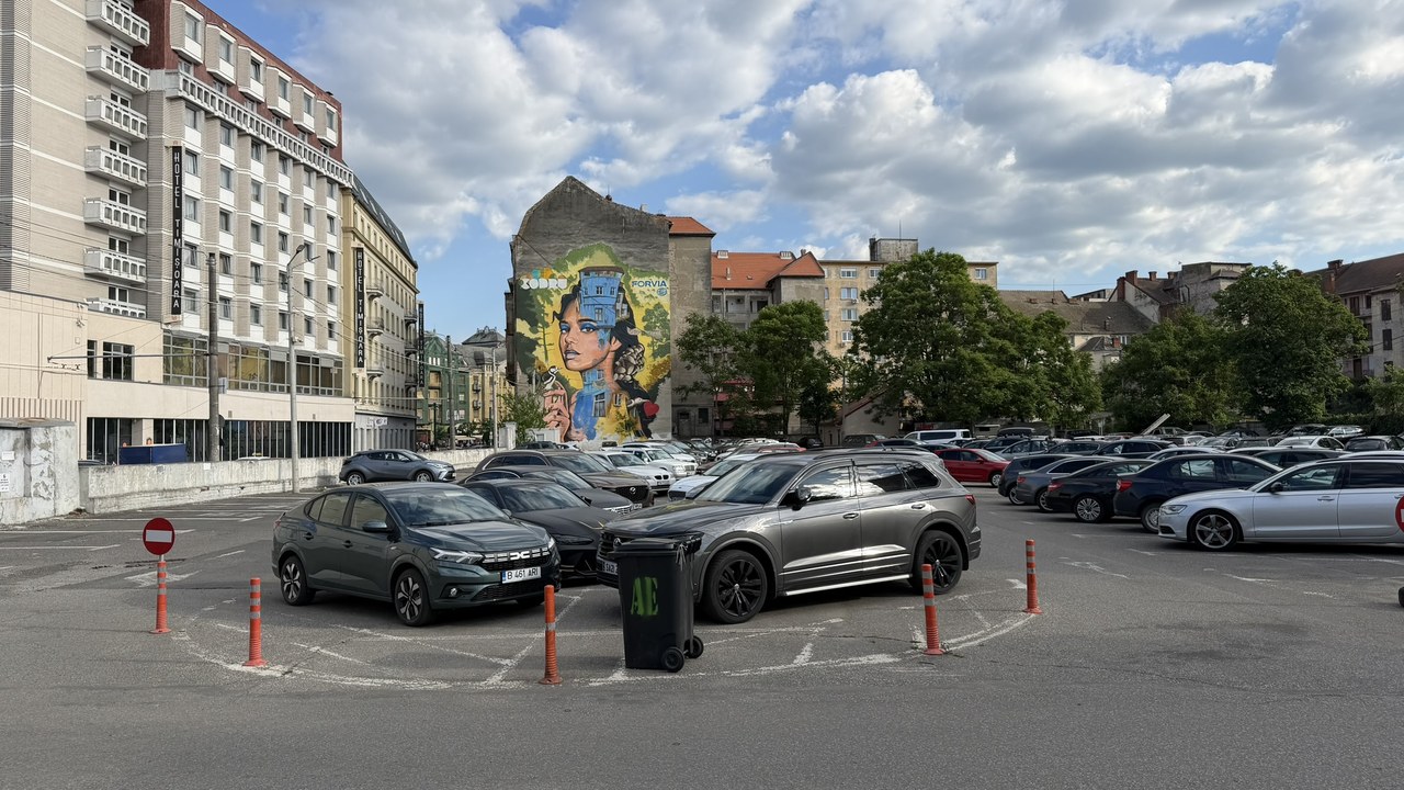 A parking lot with multiple cars sits before residential buildings and a large portrait mural, illustrating how visual landmarks help establish recognizable neighborhood identity.