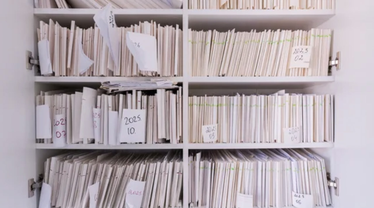White filing cabinet with labeled document compartments storing papers vertically, representing systematic organization principles used in database schema design and data structuring.