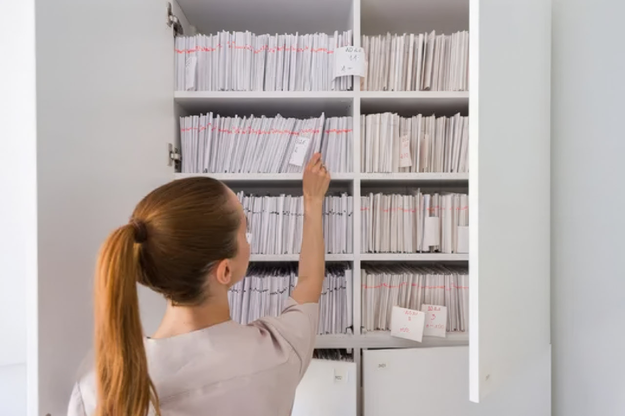 Woman reaching toward organized white folders in a shelving cabinet, illustrating the systematic organization that SEO professionals apply to directory listings for improved search visibility.
