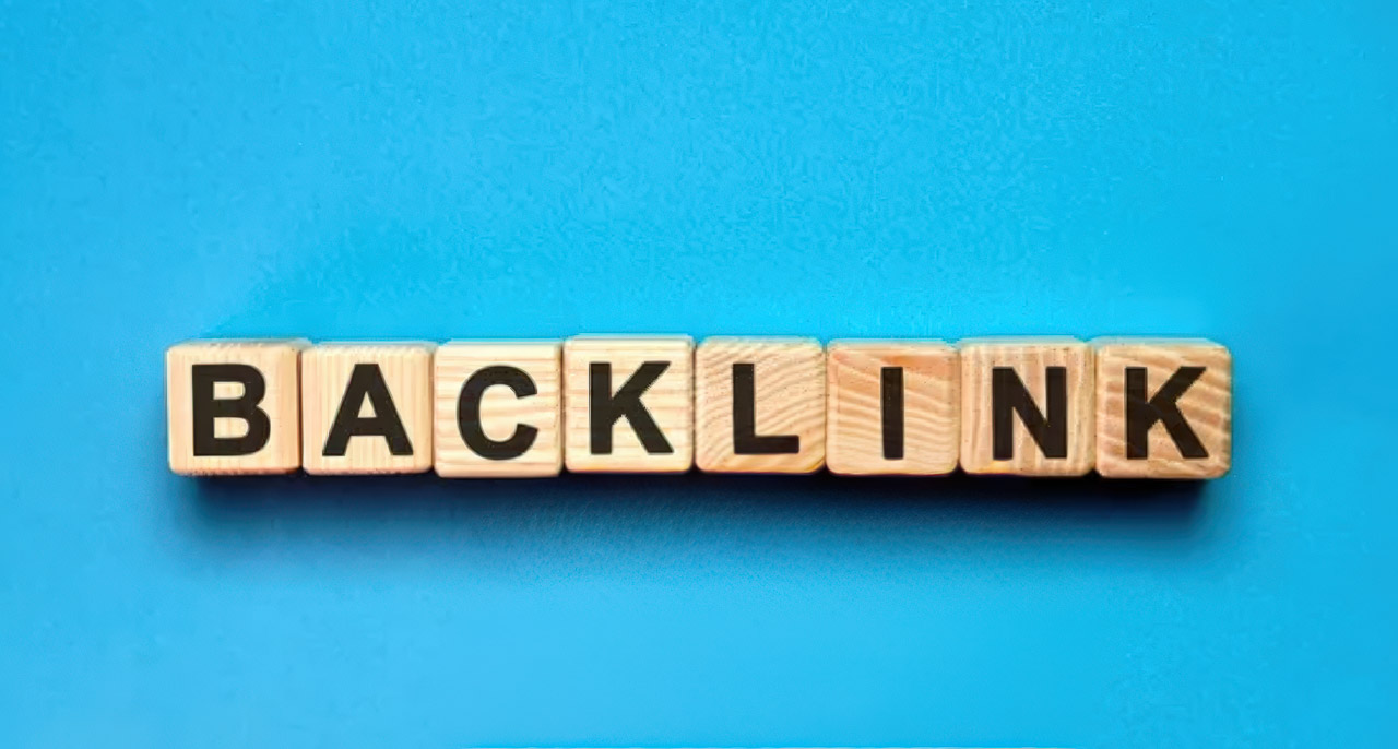 Wooden letter tiles spelling BACKLINK on a cyan background, illustrating link building and local directory strategies for boosting website authority.