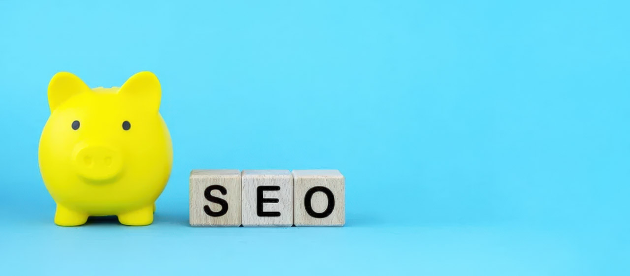 Yellow piggy bank next to wooden letter blocks spelling SEO on cyan background, representing investment in search engine optimization and local business marketing.